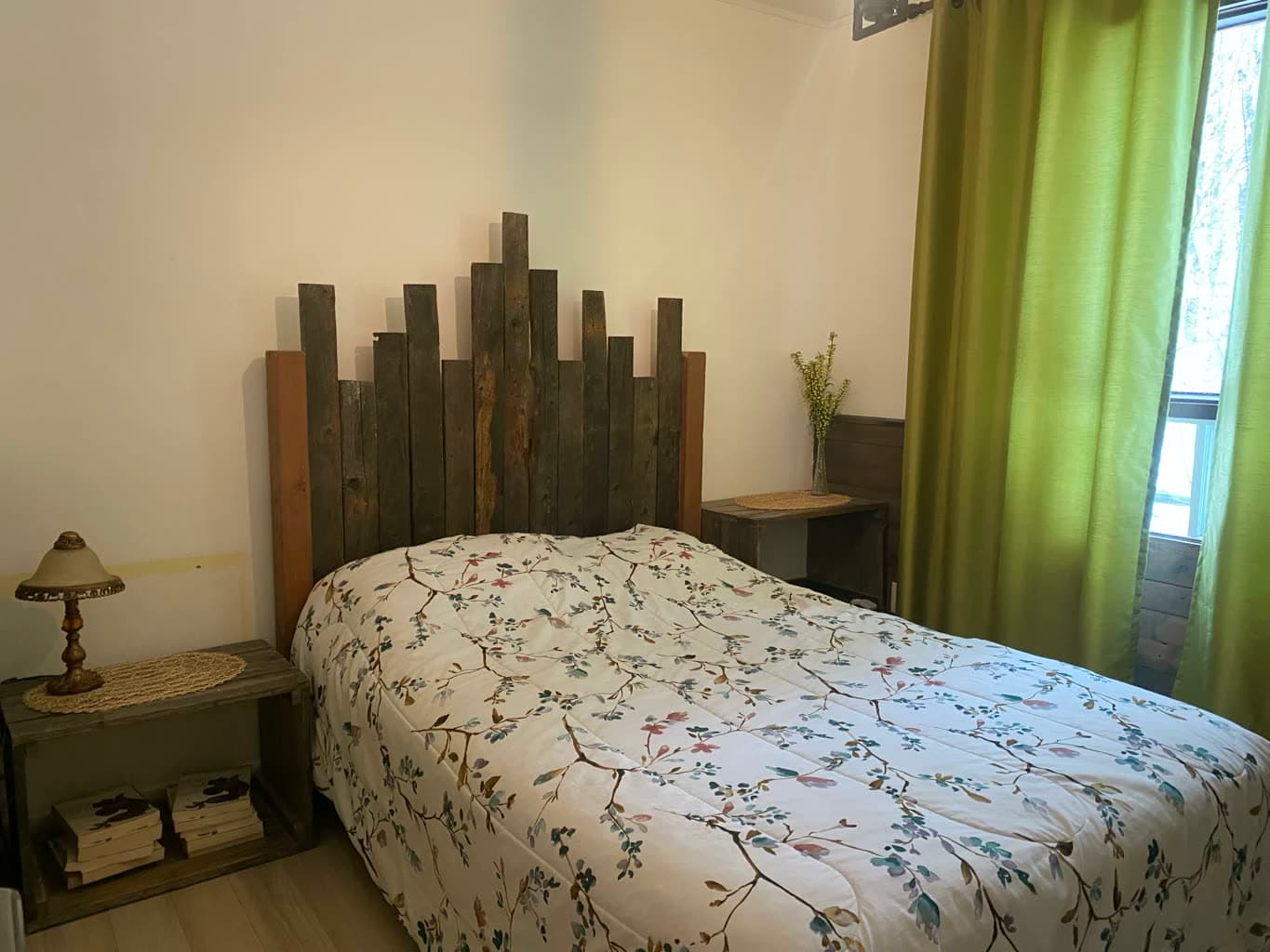 Chambre avec lit double, tête de lit en bois et rideau vert.