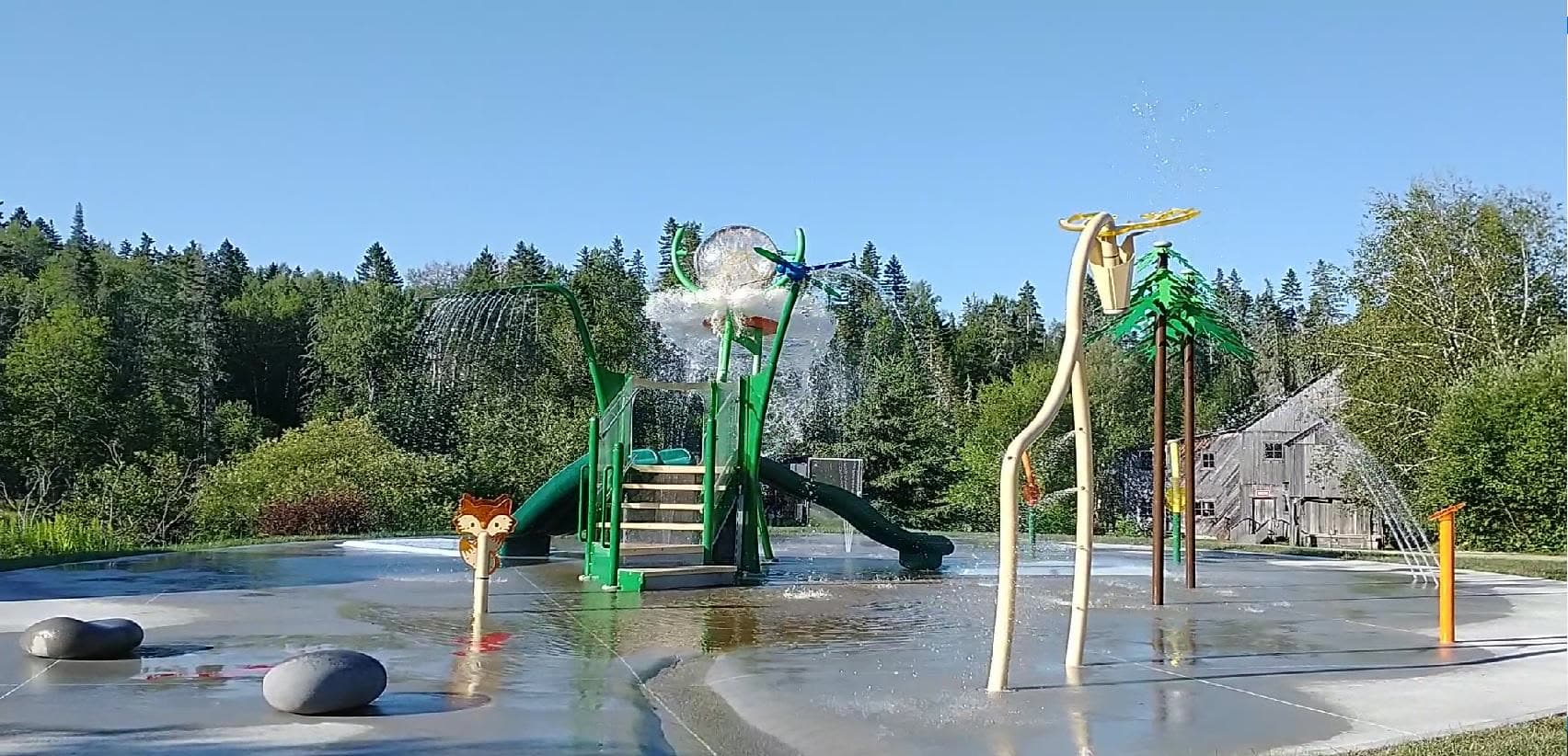 Les jeux d'eau en fonction : jets, glissade et structures vertes sur la place mouillée.