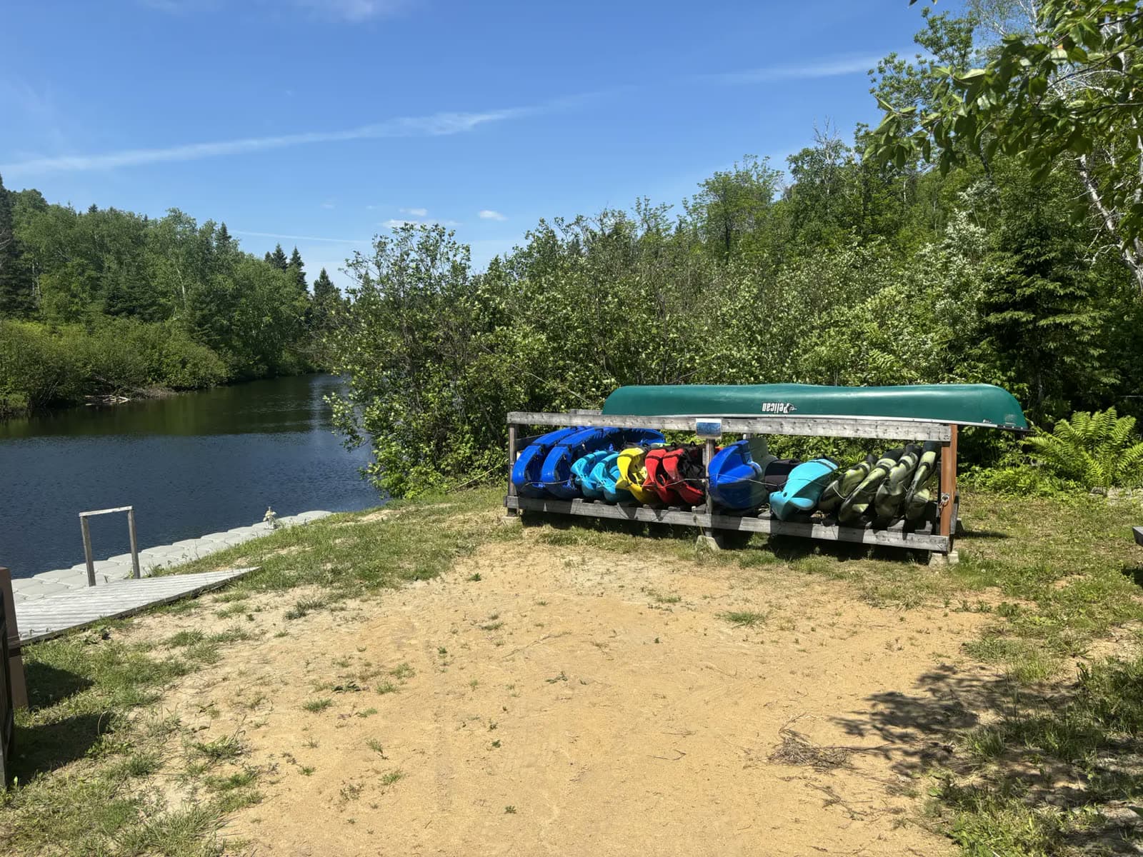 La mise à l'eau sur la rivière aux Saumons : canots et kayaks rangés sur leur support, au bord de la plage de sable.