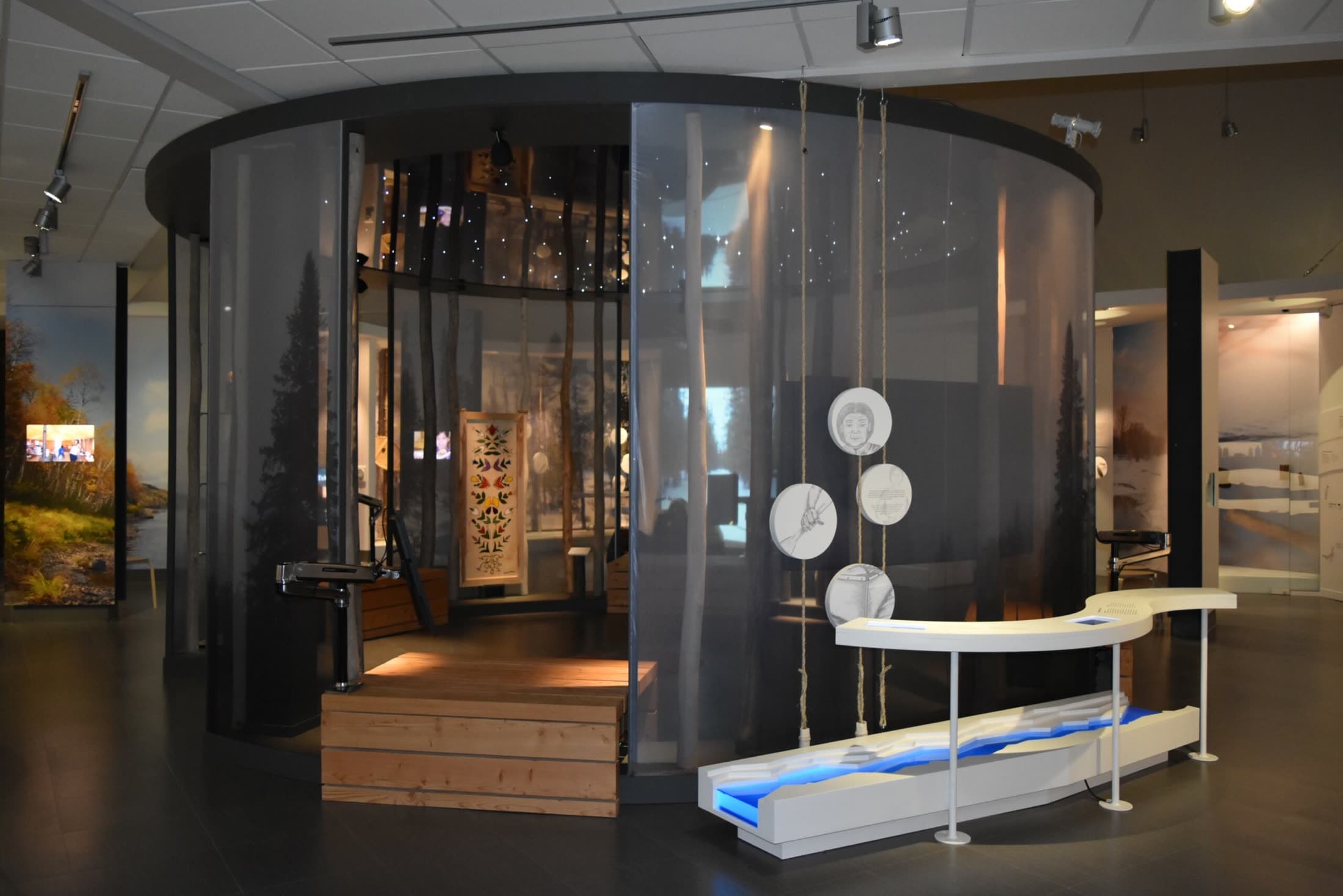 La salle d'exposition du moulin : cylindre vitré, écrans et objets d'époque.