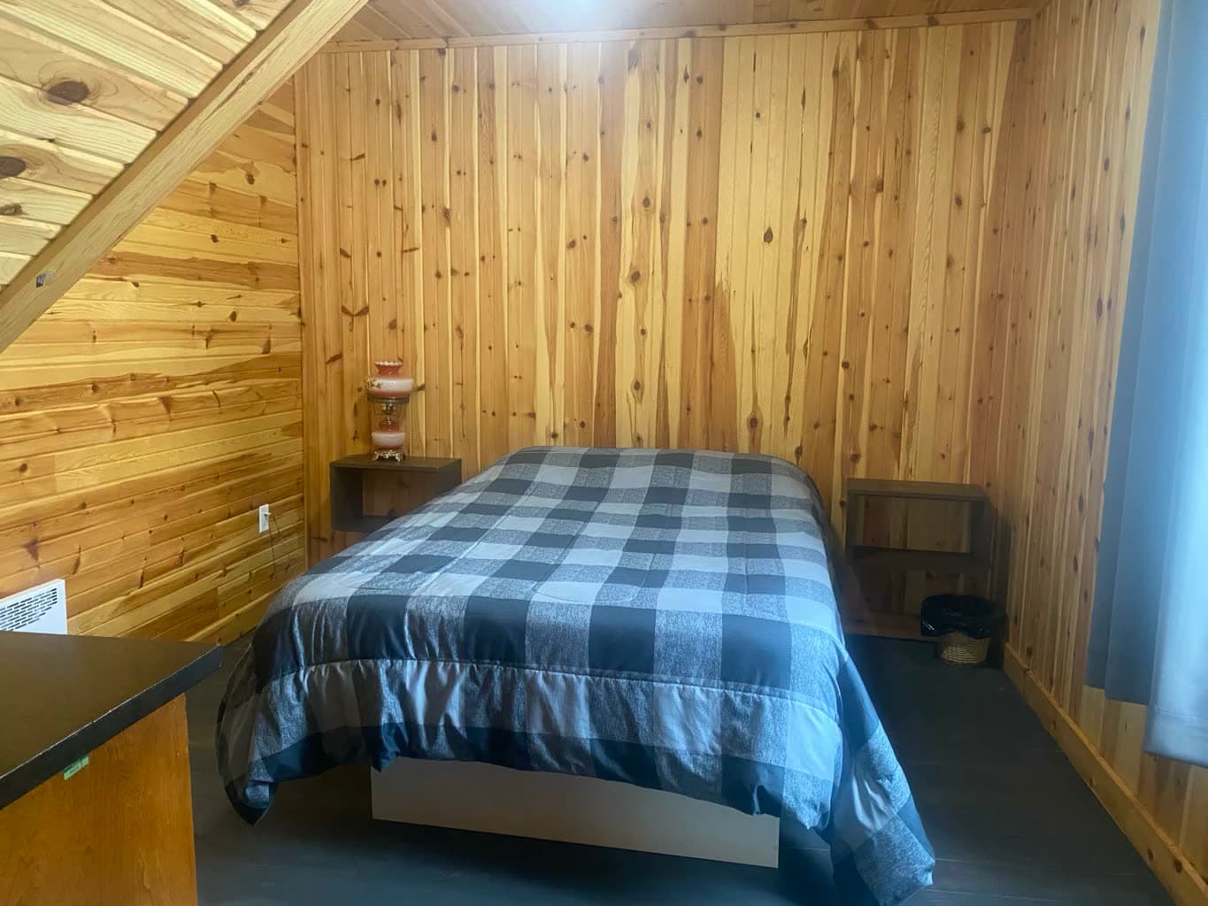 Chambre sous les combles, lit double et couvre-lit à carreaux bleus.
